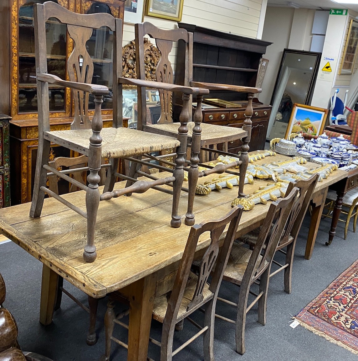 A 19th century elm plank topped kitchen dining table, on a beech underframe, the top, length 275cm, width 92cm, height 76cm, together with a set of ten oak and ask rush seated dining chairs (2 arm, 8 single)